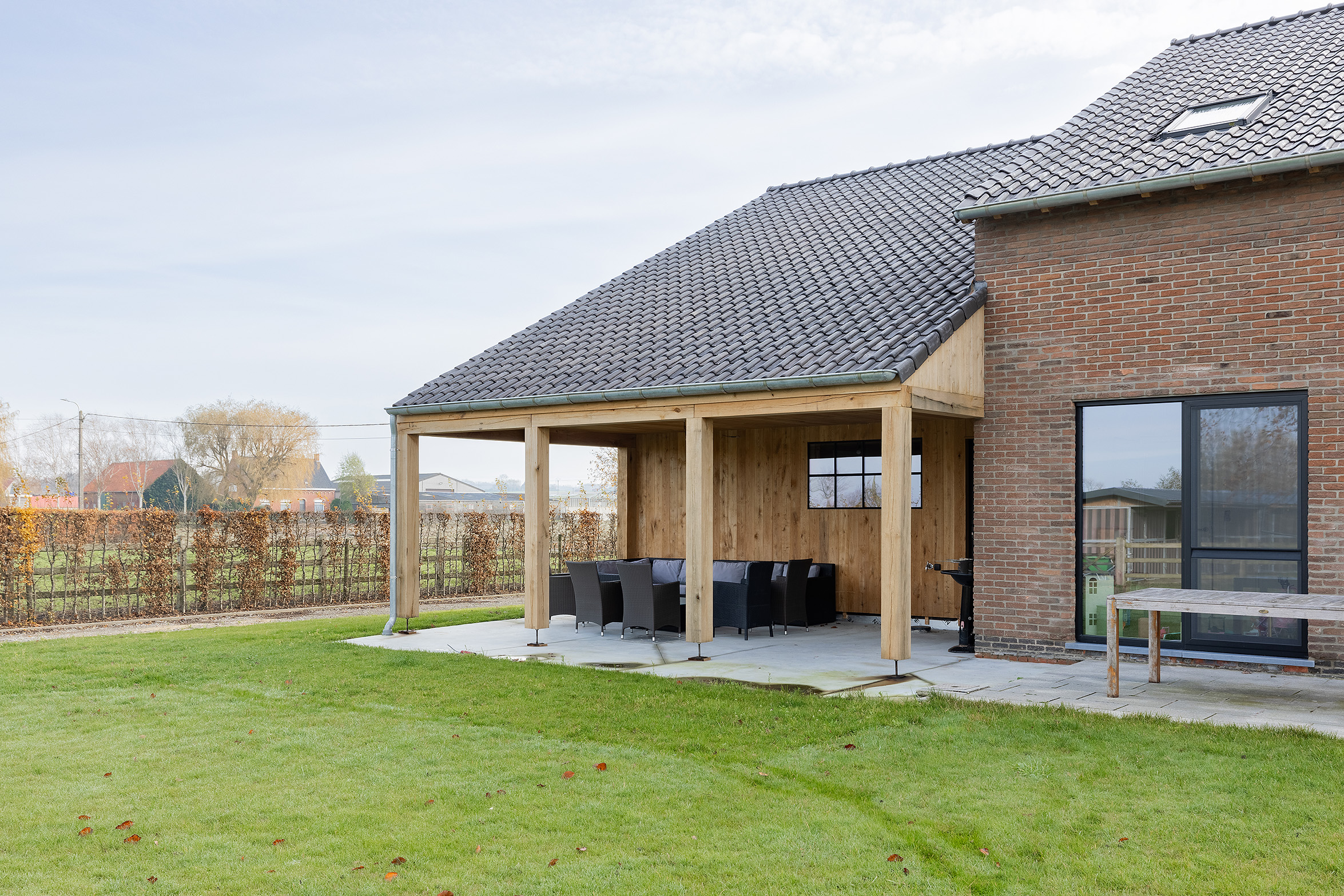 De achterkant van een woning met overdekt terras.
