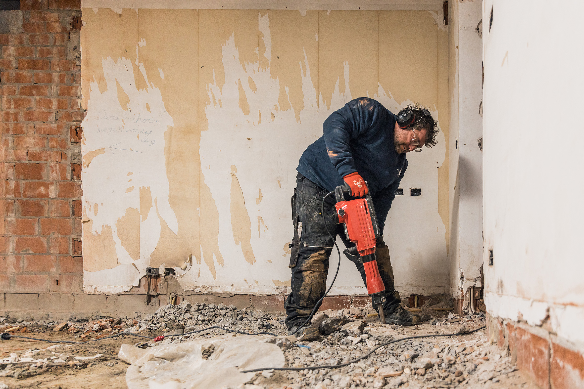 Een ervaren medewerker breekt vloeren uit op een werf.